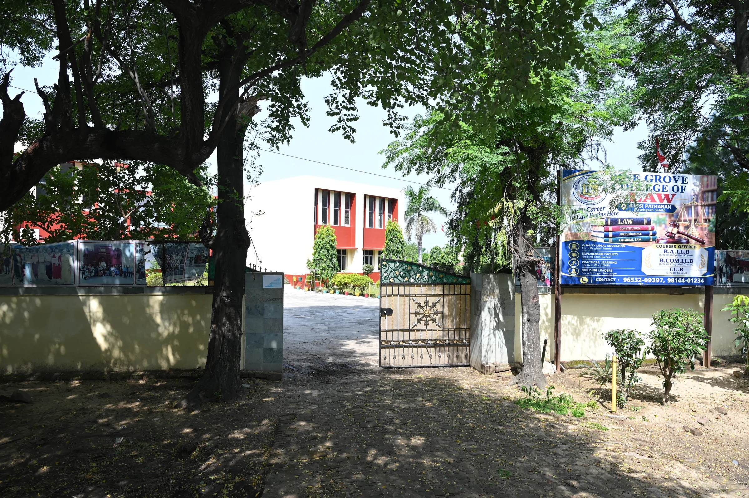 A Pine Grove college building viewed through the trees beside the campus gate.